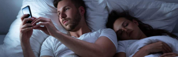 koppel ligt in bed man appt op zijn telefoon