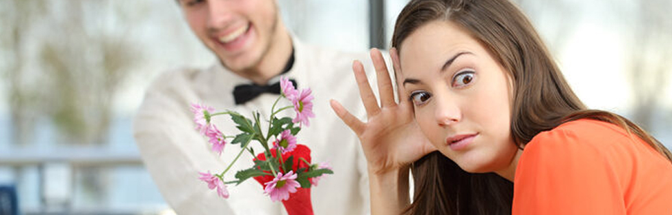 vrouw kijkt ongemakkelijk weg van een man die bloemen geeft